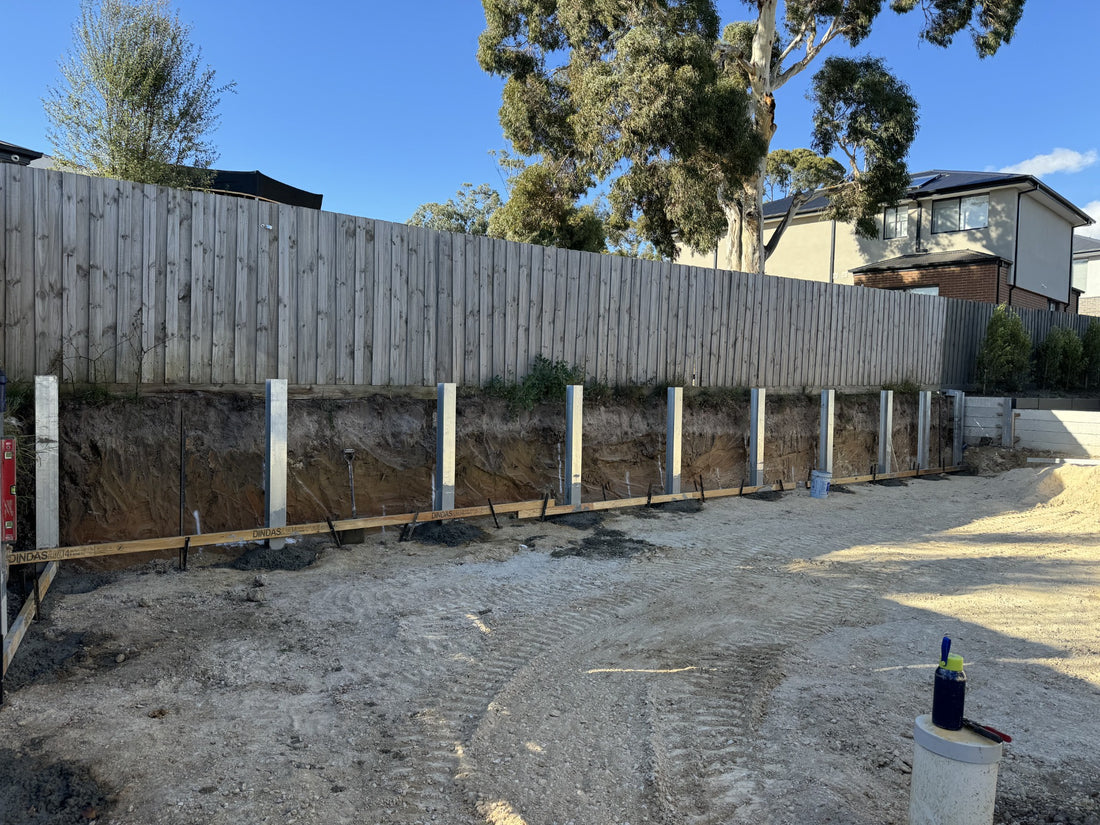 Galvanised steel posts positioned along a retaining wall boundary